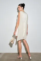 Vestido corto de satén color crema, con cuello drapeado y diseño sin mangas de corte recto y holgado.