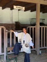 Ruana de lana merino color crudo, con diseño abierto, bolsillos frontales de cuero vacuno con textura y flecos en el ruedo.