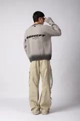 Sweater de punto acanalado con diseño degradado de negro a gris en el cuello y el ruedo. Presenta un corte regular y un pequeño bordado central en el pecho.