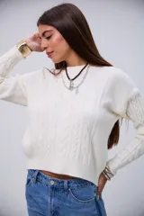 Sweater de punto color crudo con cuello redondo, diseño de ochos y mangas largas.