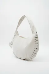 Cartera tipo hobo bag color negro, con detalles de tachas plateadas en los bordes y un charm colgante en forma de corazón también con tachas.