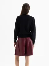 Sweater negro de tejido cálido con cuello redondo y mangas largas. Presenta un bordado frontal multicolor con motivos de fuego y flores.