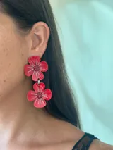 Aros colgantes con diseño de doble flor en color rojo, con detalles de glitter plateado en los pétalos y centro decorado.