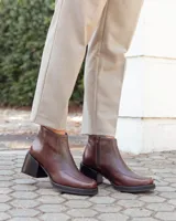 Botinetas de cuero color chocolate, con diseño de textura tipo reptil en el empeine y laterales. Presentan un taco cuadrado de altura media, suela de goma negra y cierre lateral para mayor comodidad.