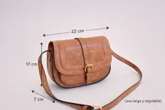 Bandolera de tamaño pequeño en color camel con acabado texturizado. Presenta un diseño de solapa frontal con detalle de hebilla decorativa y cierre magnético. Incluye una correa larga ajustable y herrajes metálicos en tono dorado.