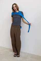 Pantalón de tiro alto con diseño balloon, presenta pliegues frontales, trabillas para cinturón, bolsillos laterales y cierre frontal con cremallera y botón.