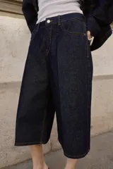 Bermuda de tiro alto confeccionada en denim azul oscuro, con diseño de pernera ancha, cinco bolsillos y cierre frontal con cremallera y botón.