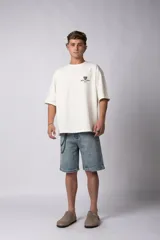 Remera de corte oversize color gris oscuro, confeccionada en algodón premium de alto gramaje. Presenta un diseño minimalista con un pequeño estampado frontal que incluye un oso y el texto 'Richer & Louder VCP'.