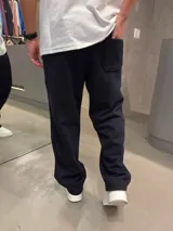 Pantalón de jogging negro de corte holgado, con cintura elástica y bolsillos laterales. Presenta un pequeño logo bordado en blanco en la parte superior izquierda.