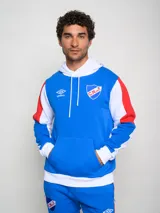 Canguro de felpa Umbro del Club Nacional de Football, con diseño tricolor en rojo, azul y blanco. Presenta capucha con cordones ajustables, bolsillo tipo canguro frontal, logo de la marca y escudo del club bordados en el pecho.