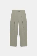 Pantalón de tiro alto con diseño tipo barrel, presenta pliegues frontales pronunciados, bolsillos laterales y cierre frontal con cremallera, botón interior y gancho metálico oculto.