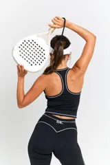 Conjunto deportivo compuesto por un top de escote halter y pantalón de corte acampanado, ambos en color negro con detalles de líneas blancas contrastantes. El top presenta un diseño ajustado con logo estampado en el frente, mientras que el pantalón cuenta con una cintura alta y diseño fluido.