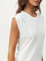 Remera blanca de corte clásico con cuello redondo y mangas cortas con detalle de hombreras.