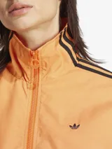 Campera deportiva Adidas Originals Firebird, color naranja con degradado, corte holgado, cierre frontal completo, cuello y puños acanalados, y las tres líneas negras características de la marca en las mangas.