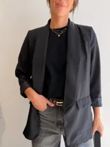 Blazer sastrero de corte clásico con solapas frontales y bolsillos con solapa. Presenta mangas largas con puños vueltos y un diseño forrado que ofrece una caída estructurada y elegante.