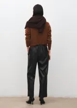Pantalón negro de cuero sintético, de tiro medio con cintura elástica ajustable mediante cordón y diseño de pernera recta.