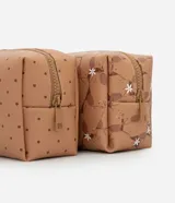 Kit de tres neceseres organizadores. Incluye un neceser grande transparente con bordes en tono tostado y dos neceseres más pequeños estructurados, uno con estampado de puntos y otro con estampado de carpinchos y flores blancas. Todos cuentan con cierre superior.