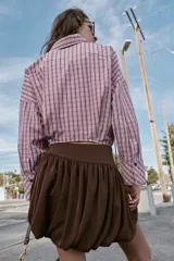 Falda corta de tiro alto con diseño abullonado tipo globo, confeccionada en tejido satinado de color marrón con cierre lateral oculto.