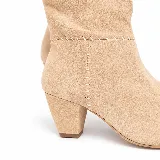 Botas cortas de gamuza color beige, con punta fina, taco ancho y costuras decorativas visibles en forma de cruz.