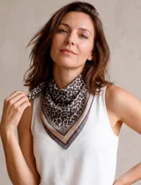 Pañuelo cuadrado de satén con estampado animal print y bordes en tonos neutros. Presenta un diseño versátil y ligero.