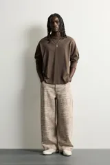 Pantalón relaxed fit de algodón con estampado animal print de cocodrilo en tonos beige y gris. Tiene diseño de cinco bolsillos, cierre frontal con cremallera y botón, y una tira con bolsillo multifunción en la pernera.