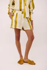 Short de lino italiano con estampado a rayas verticales en tonos amarillo y blanco, con bolsillos laterales y cintura elástica.