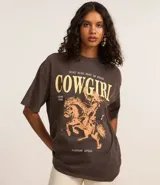 Remera de algodón con efecto lavado vintage, cuello redondo y mangas cortas. Presenta una estampa frontal contrastante con diseño de una mujer montando a caballo y lettering con la palabra Cowgirl.