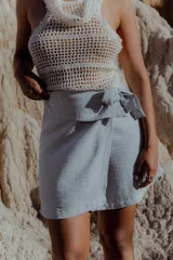 Minifalda celeste de lino y poliéster, con corte cruzado y lazo lateral.