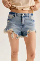 Short de denim azul con diseño de distintos lavados tipo patchwork, talle medio y ruedo deshilachado y desestructurado con roturas.