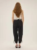 Pantalón de lyocell color tostado, con silueta relajada, bolsillos laterales y detalles de costuras pespunteadas. Cuenta con puños ajustables en los tobillos mediante cordones y elástico.