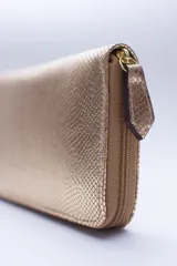 Billetera rectangular con cierre perimetral, confeccionada en cuero con textura de reptil. Cuenta con múltiples compartimentos internos para tarjetas, documentos y billetes, además de un bolsillo interior con cierre para monedas.