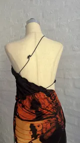 Minivestido con estampado de mariposas en tonos naranja y negro. Diseño ajustado con escote halter asimétrico y abertura en la cintura.