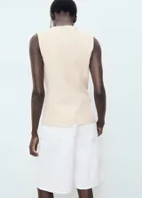 Chaleco de corte recto y diseño sin mangas, con cuello redondo y tirantes anchos. Presenta un cierre frontal con botones y forro interior de algodón.