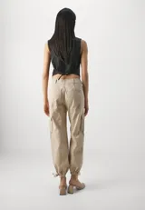 Pantalón cargo color beige de tiro alto, con bolsillos laterales con solapa y ajuste con lazos en los tobillos.