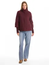 Tapado de tejido bouclé color marrón, con silueta evasé y largo a la cadera. Presenta cuello alto envolvente, cierre frontal oculto con botones a presión y bolsillos frontales de gran tamaño. Sus mangas son 3/4 con corte amplio y puños de tejido rib al tono que se extienden para cubrir las muñecas.