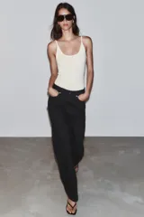 Jeans de tiro alto, pernera recta y larga, estilo clásico con cinco bolsillos, cierre frontal con cremallera y botón metálico.