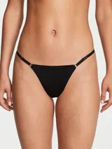Panty tipo tanga negro de tiro bajo, confeccionado en microfibra suave, con tiras laterales ajustables y argollas doradas.