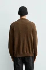 Sobrecamisa de punto con mezcla de lana y fibra de alpaca, color marrón. Presenta cuello solapa, cierre frontal con botones, manga larga y bolsillo plastrón en el pecho. Acabados en rib en puños y ruedo.