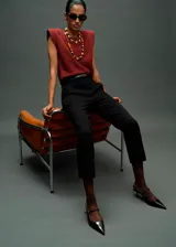 Blusa de color bordó con cuello barco y hombreras marcadas que crean una silueta estructurada. Presenta un diseño recto sin mangas con detalle fruncido en los hombros.