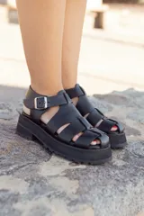 Sandalias negras de cuero con plataforma y tiras anchas entrecruzadas.