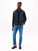 Campera azul marino de poliéster con cuello inglés, cierre frontal de cremallera, dos bolsillos laterales con cremallera y puños con cierre a presión. Presenta un logo de Tommy Hilfiger bordado en el pecho.