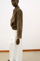 Cazadora de efecto ante con cuello solapa, cierre frontal con cremallera y mangas por debajo del codo. Presenta bolsillos delanteros de plastrón con solapa y bajo elástico.