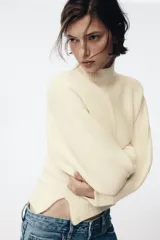 Jersey de punto liso con cuello subido, manga larga y detalle de costura vertical marcada en el frente. Presenta terminaciones en rib en puños, cuello y ruedo.