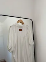 Vestido camisero blanco, holgado, con mangas 3/4 y puños elásticos.
