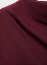 Vestido midi de color bordó, sin mangas, con cuello redondo y diseño entallado. Presenta un detalle de fruncido lateral en la cintura y cierre posterior.