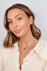Collar corto de cuentas circulares de piedra natural beige combinadas con pequeñas cuentas cilíndricas de cristal checo en tonos azul y rojo.