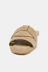 Sandalia plana color beige con tiras cruzadas en la parte delantera.