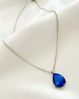 Collar plateado con dije en forma de lágrima de cristal azul.