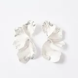 Aros tipo caravanas con diseño de pétalos de flor en color plateado, con textura estriada y acabado brillante.