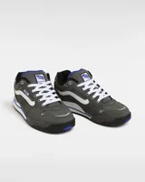 Zapatillas Vans Rowley XLT de color gris oscuro, con la franja lateral Sidestripe en blanco, pasador de cordones con etiqueta de la marca y detalles en azul. Presentan diseño robusto inspirado en el skate de los años 90 y 2000, con lengüeta acolchada y suela combinada en blanco y negro.